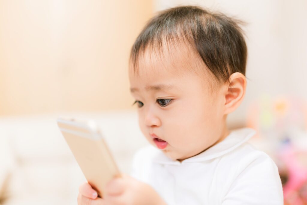スマートフォンを見つめる幼い子どもの写真。子ども用GPSの選び方をイメージ。