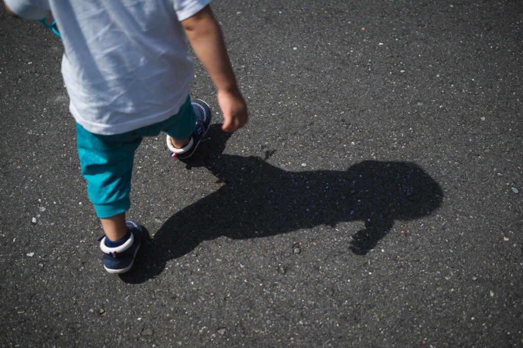 歩く子どもの足元と影の写真。登下校や外出時の安全を考えるイメージ。